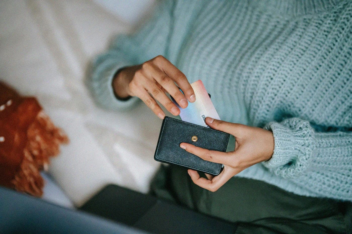 Mujer con una tarjeta en la mano mientras usa su teléfono